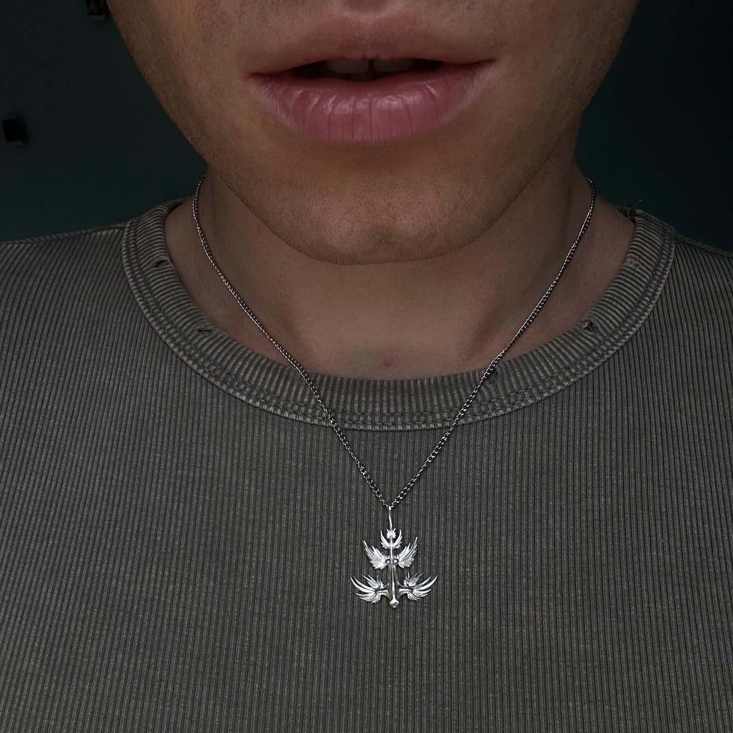 Close-up of a person wearing the Glaucus atlanticus necklace with a silver pendant resembling the Blue Dragon, styled casually with a ribbed shirt. The design highlights the detailed craftsmanship and versatility of the jewelry.